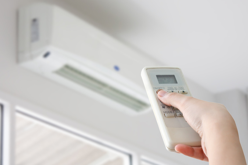 Hand with remote control directed on air conditioning system